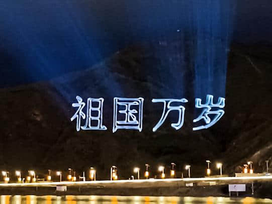 Outdoor laser text projection illuminating a mountainside during the Tibet anniversary celebrations